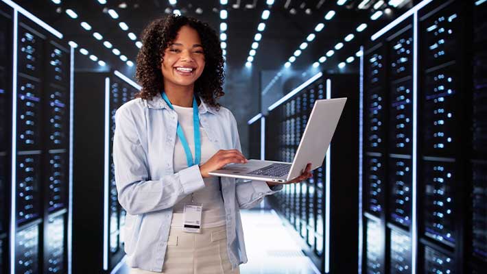 Fachinformatikerin für Systemintegration arbeitet mit einem Laptop in einem modernen Rechenzentrum zwischen Serverracks. Das Bild symbolisiert die vielfältigen Karrierechancen in der IT – von Systemadministration über Cloud Computing bis hin zu IT-Sicherheit – sowie die attraktiven Zukunftsperspektiven für Berufseinsteiger und Quereinsteiger.