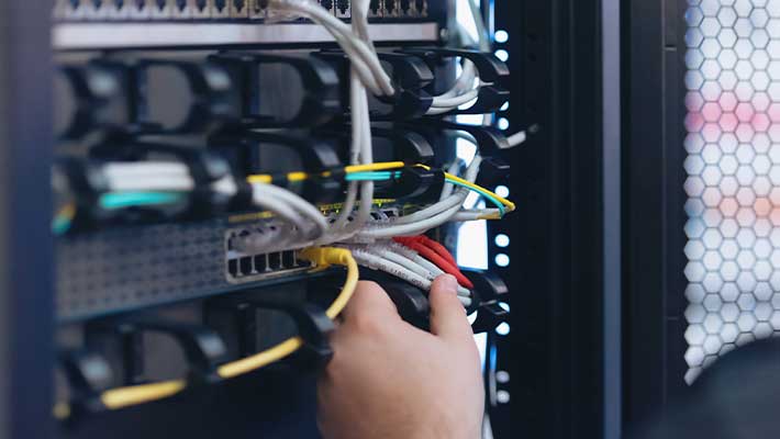 Nahaufnahme eines Fachinformatikers für Systemintegration bei der Verkabelung eines Netzwerkschranks. Das Bild zeigt die Arbeit an Servern, Netzwerken und IT-Infrastrukturen in Unternehmen, Behörden, Rechenzentren oder bei IT-Dienstleistern und verdeutlicht die zentrale Rolle von FISI beim sicheren und zuverlässigen Betrieb moderner IT-Systeme.