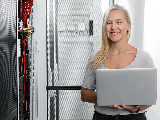 Eine Frau mit Laptop lernt in der Umschulung Fachinformatiker Systemintegration wie man IT-Systeme und Netzwerke plant, installiert, wartet und verwaltet.