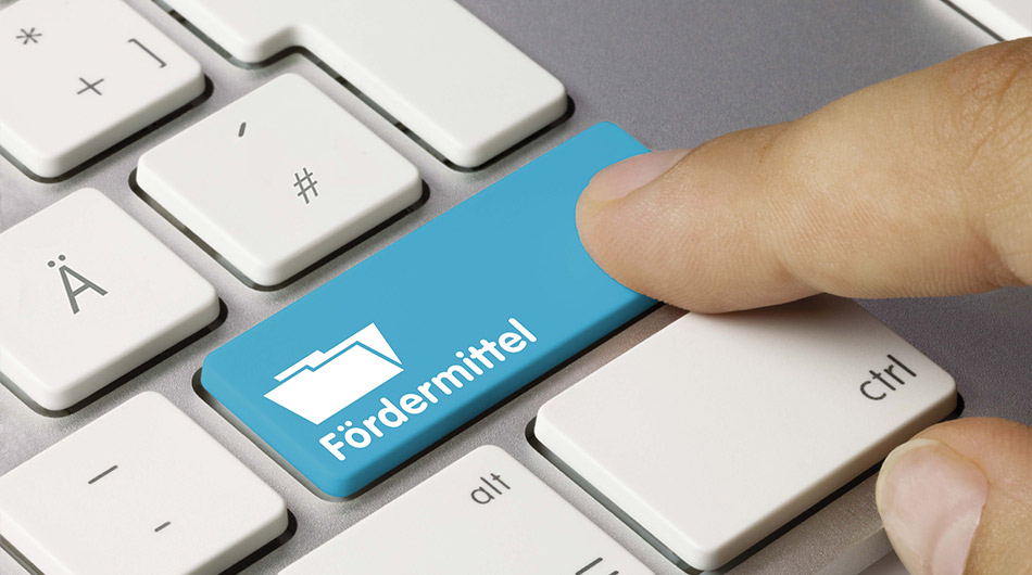 Ein Finger tippt auf einer Tastatur auf die Taste "Fördermittel"