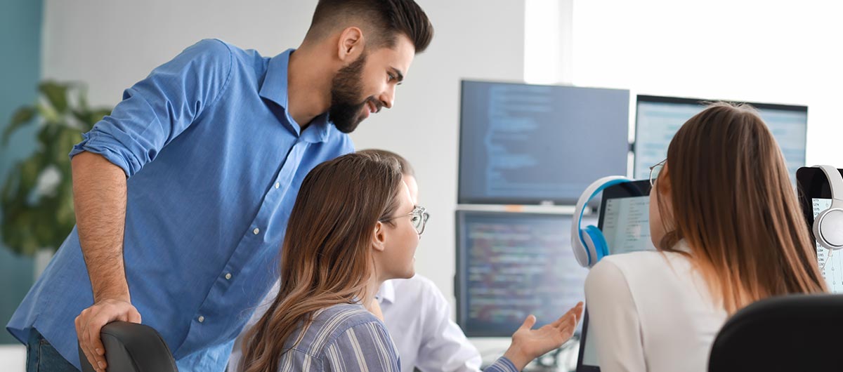 Ein Team sitzt vor einem Computer und bespricht ein Projekt.