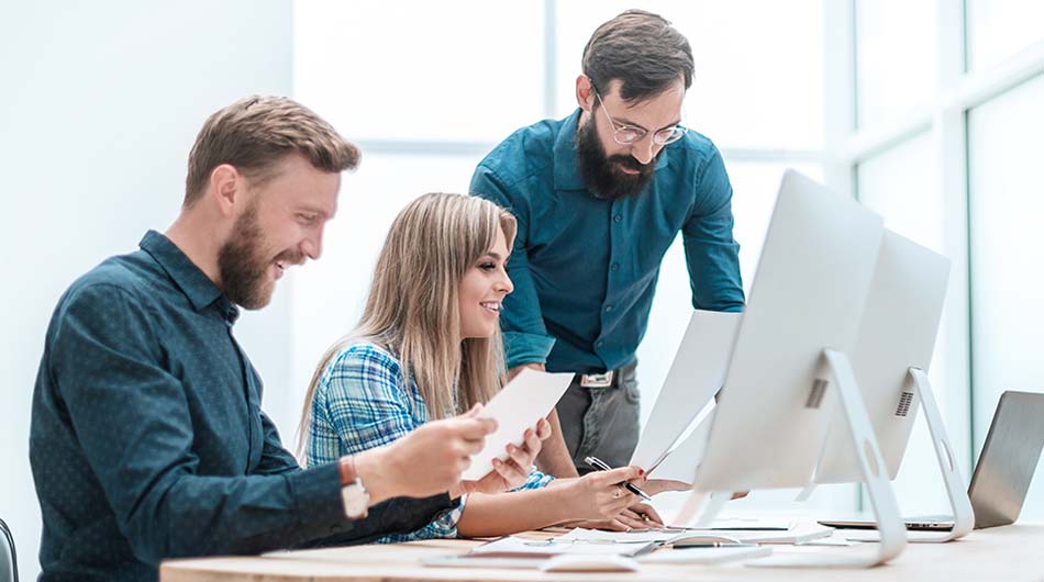 Eine Gruppe Teilnehmer sitzt in einer Umschulung vor dem Computer und erarbeiten eine Gruppenaufgabe.