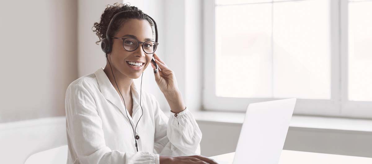 Frau mit Laptop und Headset am Tisch, Lächelnd, Weiterbildungen, IT-Admin, IT-Grundlagen, Medien, Wesdesigner, Online Marketing, Projektmanagement, SAP, Softwareentwicklung, GFN